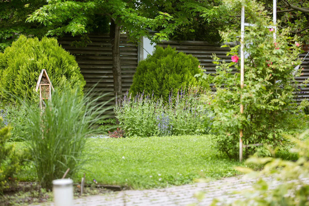 Gartenraum mit vielfältiger Bepflanzung, Vogelhaus und Steinweg
